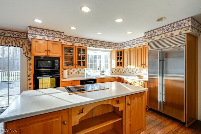 kitchen featuring dark wood finished floors, a kitchen island, brown cabinets, and black appliances