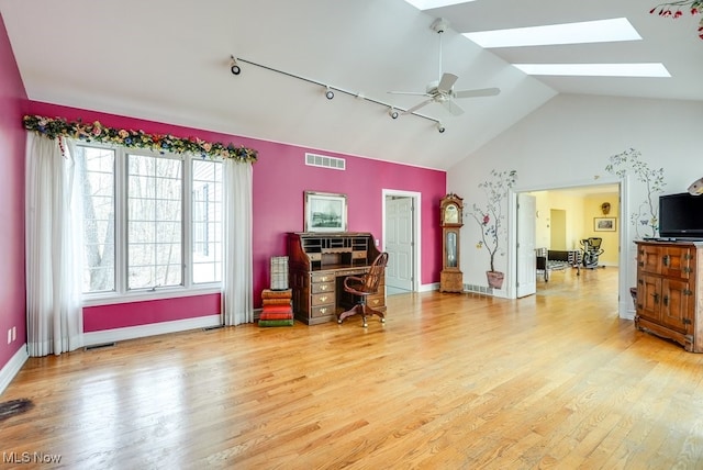 miscellaneous room with lofted ceiling with skylight, visible vents, light wood finished floors, and ceiling fan