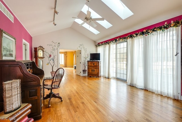 home office with lofted ceiling with skylight, visible vents, and light wood finished floors