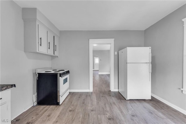 kitchen featuring dark countertops, white cabinetry, white appliances, light wood finished floors, and baseboards