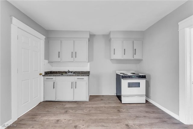 kitchen featuring electric range, light wood-style floors, white cabinets, and a sink