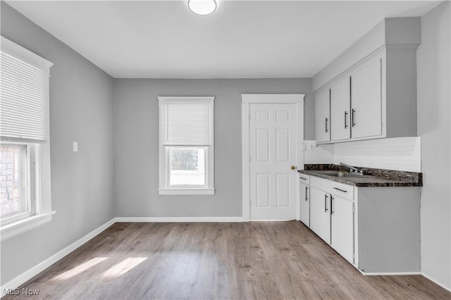 bar featuring light wood-style floors, baseboards, and a sink