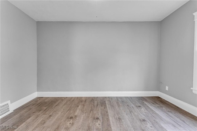 spare room with visible vents, baseboards, and wood finished floors