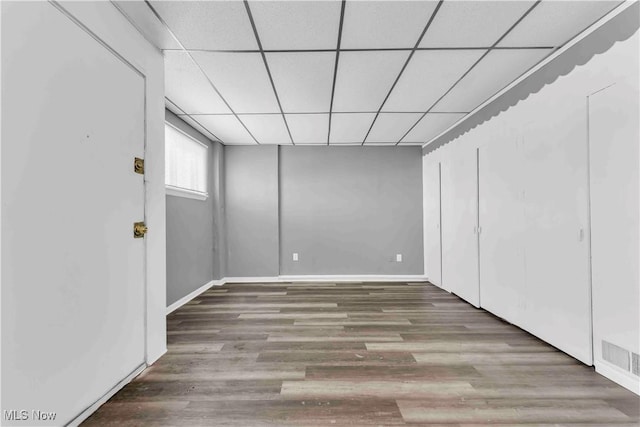 unfurnished bedroom with visible vents, wood finished floors, baseboards, and a drop ceiling