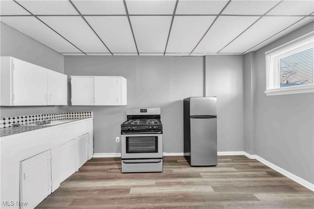 kitchen featuring white cabinets, a paneled ceiling, light wood-type flooring, and stainless steel appliances