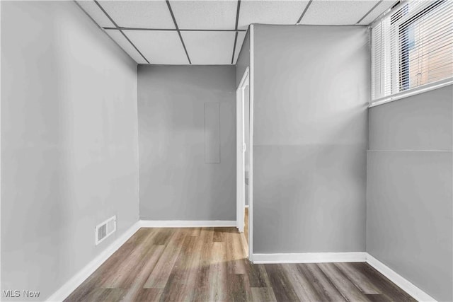 unfurnished room featuring a drop ceiling, baseboards, visible vents, and wood finished floors