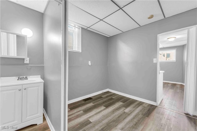 bathroom with a drop ceiling, baseboards, and wood finished floors