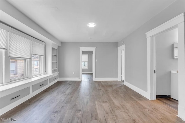 unfurnished room featuring light wood finished floors, plenty of natural light, and baseboards