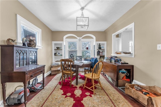 dining room with a notable chandelier, baseboards, and wood finished floors