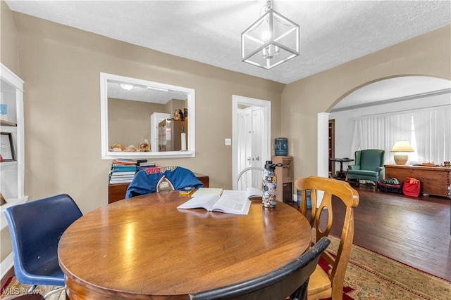 dining area with wood finished floors and arched walkways