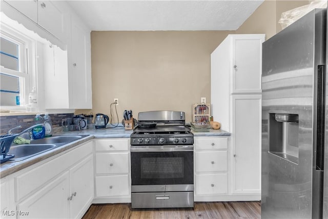 kitchen featuring white cabinetry, wood finished floors, appliances with stainless steel finishes, and a sink