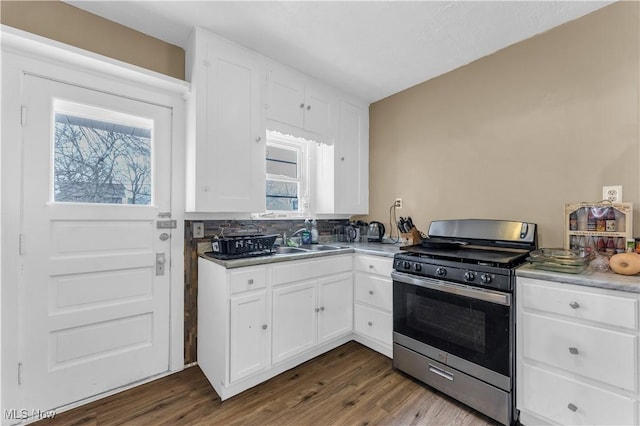 kitchen featuring a sink, stainless steel gas stove, dark wood finished floors, and white cabinetry