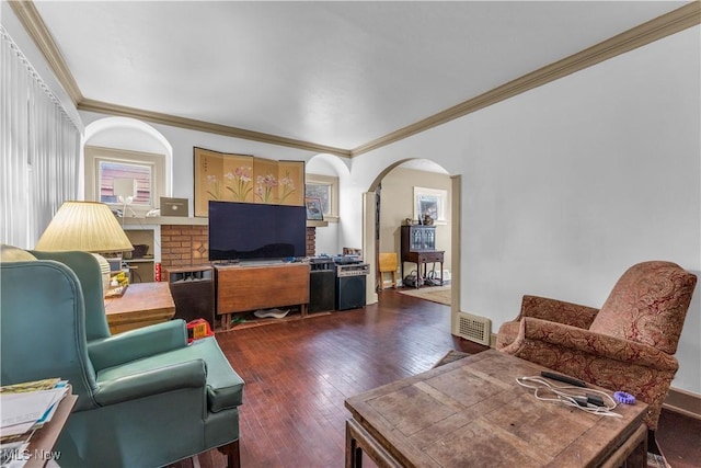 living area with dark wood finished floors, crown molding, visible vents, and arched walkways