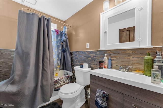 full bathroom with vanity, shower / bath combo with shower curtain, wainscoting, tile walls, and toilet