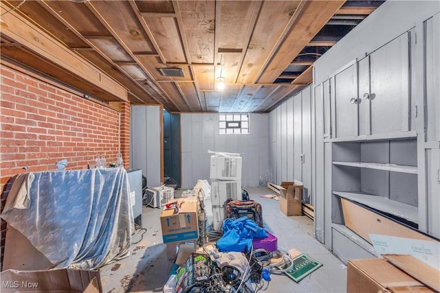 basement featuring visible vents and brick wall