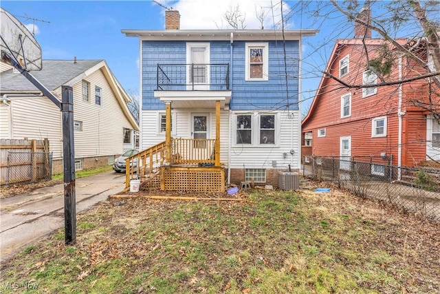 rear view of house featuring central AC, a chimney, a balcony, and fence