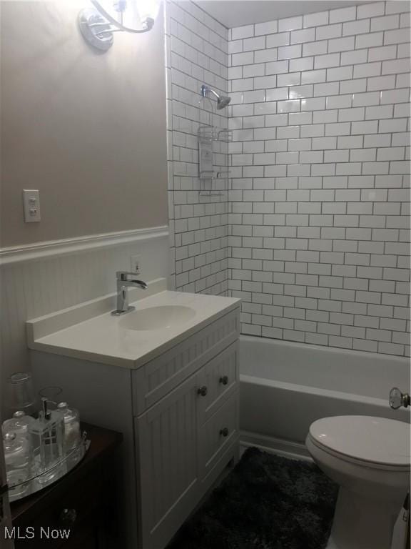 full bathroom with vanity, bathing tub / shower combination, toilet, and wainscoting