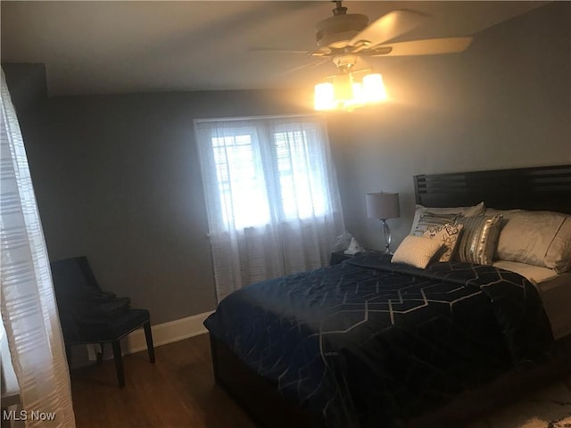 bedroom featuring baseboards, wood finished floors, and a ceiling fan