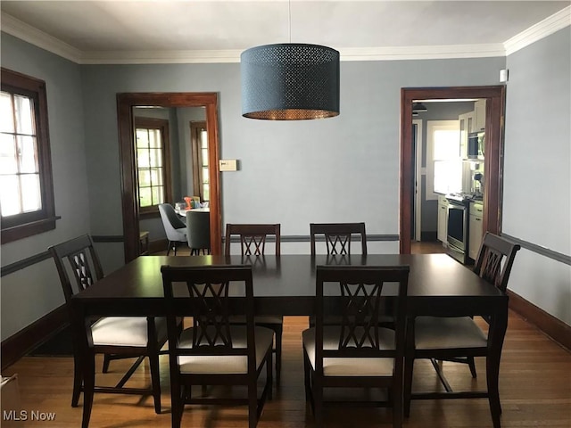 dining area with wood finished floors, baseboards, and ornamental molding