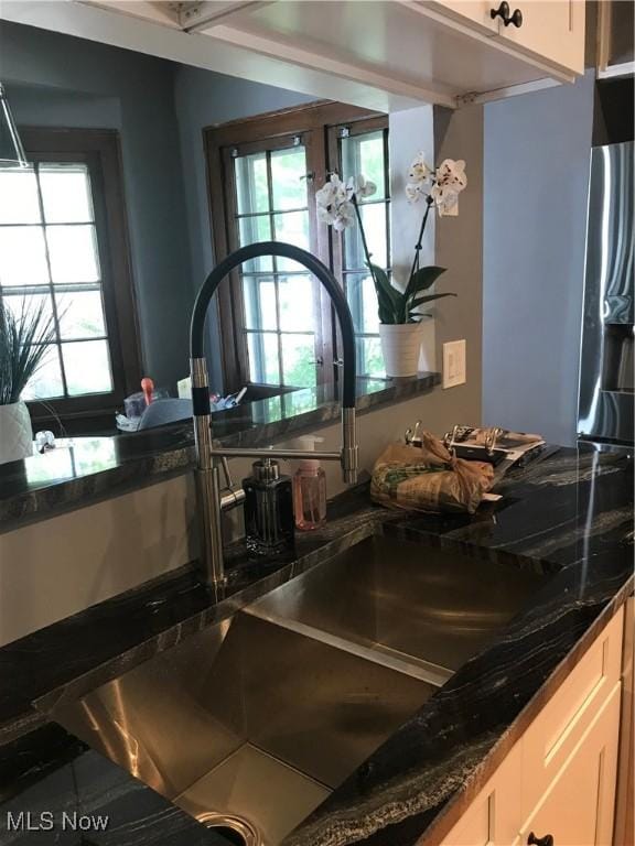 interior details with dark stone countertops, white cabinets, and a sink