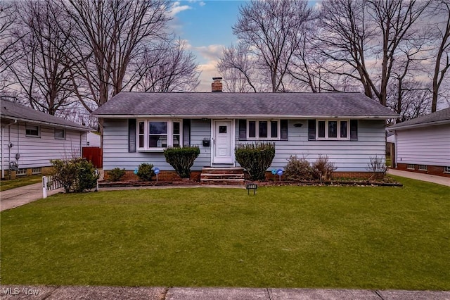 ranch-style house featuring a chimney, a front lawn, and roof with shingles