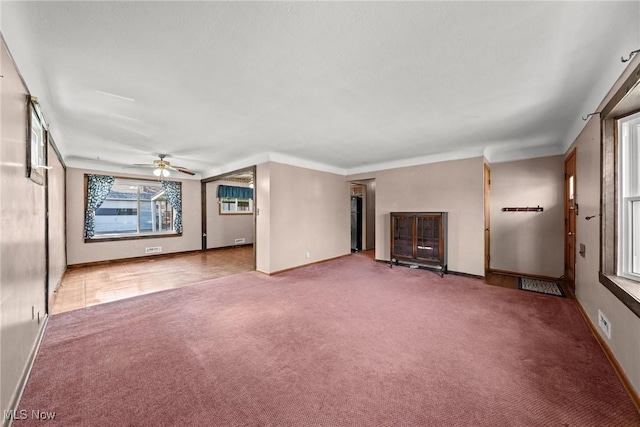 unfurnished living room with baseboards, ceiling fan, and carpet floors