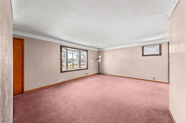 spare room with baseboards, carpet, visible vents, and a textured ceiling