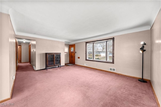 unfurnished living room with a glass covered fireplace, visible vents, baseboards, and carpet floors