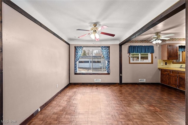 unfurnished room with a sink, visible vents, baseboards, and a ceiling fan