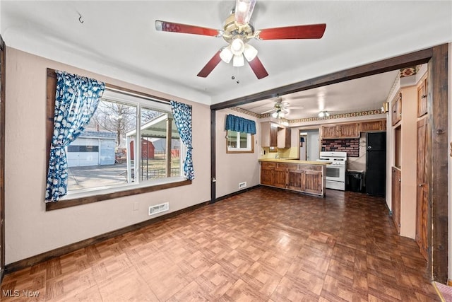 kitchen featuring visible vents, white range with gas stovetop, brown cabinets, a peninsula, and a ceiling fan