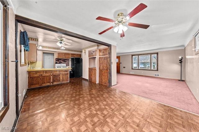 unfurnished living room featuring baseboards, visible vents, and ceiling fan