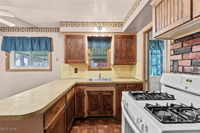 kitchen with a sink, a ceiling fan, tasteful backsplash, and white gas range oven