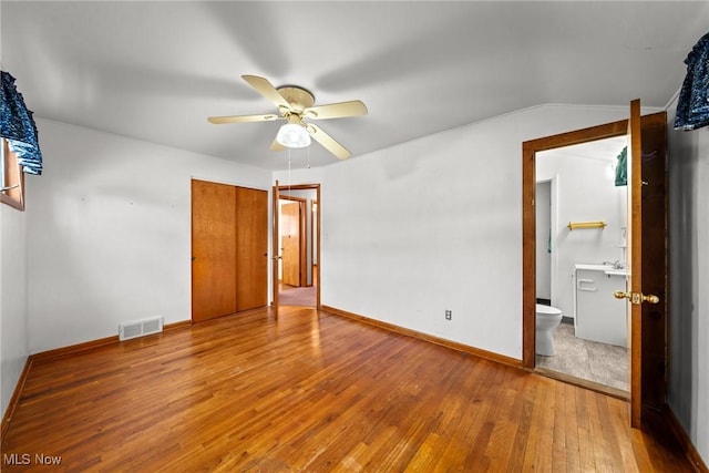 unfurnished bedroom featuring visible vents, a ceiling fan, wood-type flooring, baseboards, and vaulted ceiling