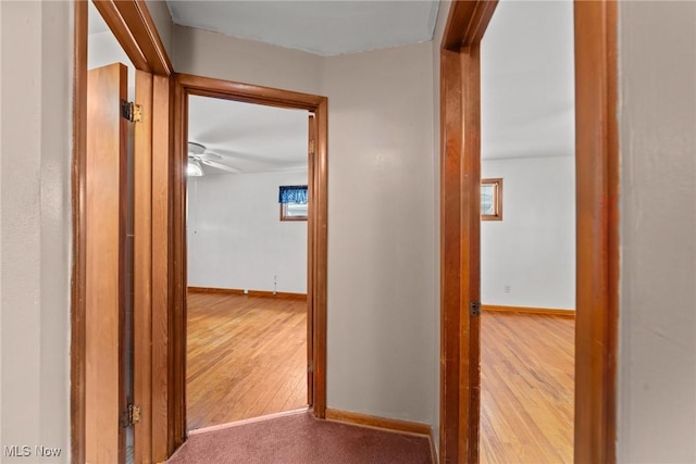 corridor featuring baseboards and wood finished floors