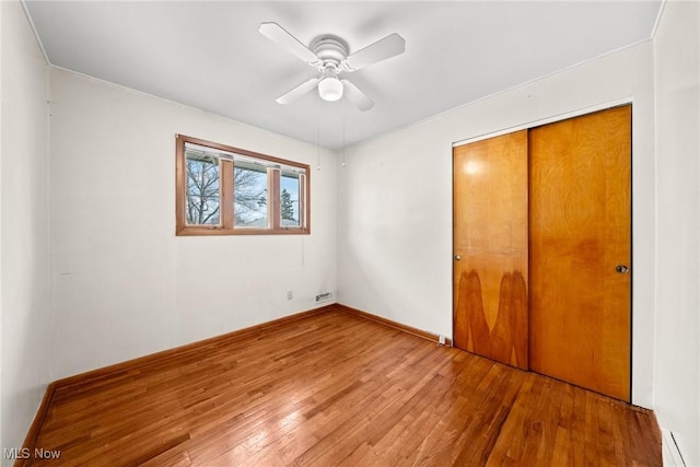 unfurnished bedroom with a closet, wood-type flooring, and ceiling fan