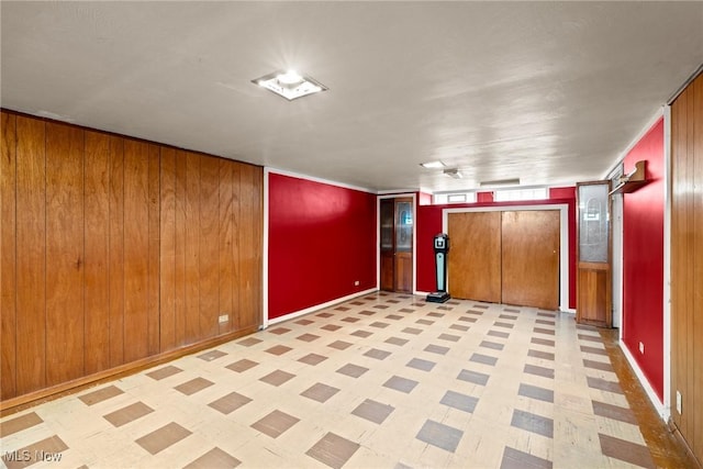 spare room featuring tile patterned floors, baseboards, and wood walls