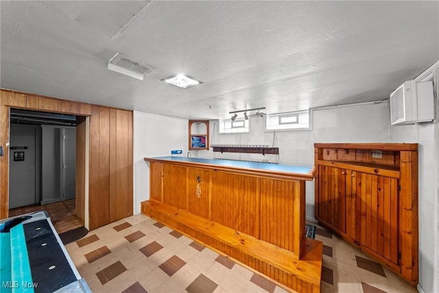 bar with an AC wall unit, wooden walls, light floors, and visible vents