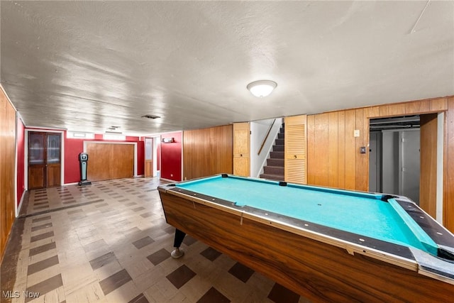 playroom with tile patterned floors, elevator, wood walls, and billiards