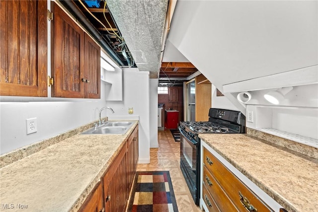 kitchen with light countertops, gas stove, brown cabinets, and a sink