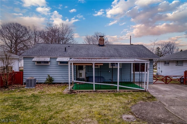 rear view of house featuring a shingled roof, fence, central air condition unit, a chimney, and a yard