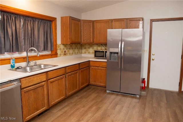 kitchen featuring light countertops, stainless steel appliances, light wood finished floors, and a sink