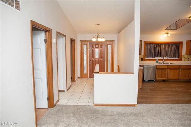 interior space with brown cabinets, visible vents, stainless steel dishwasher, a chandelier, and light colored carpet