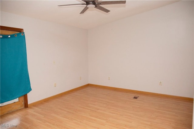 empty room with baseboards, a ceiling fan, and light wood-style floors