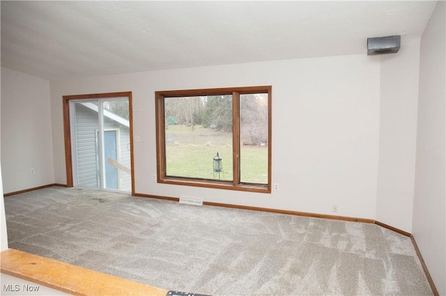 unfurnished room with carpet floors, visible vents, and baseboards