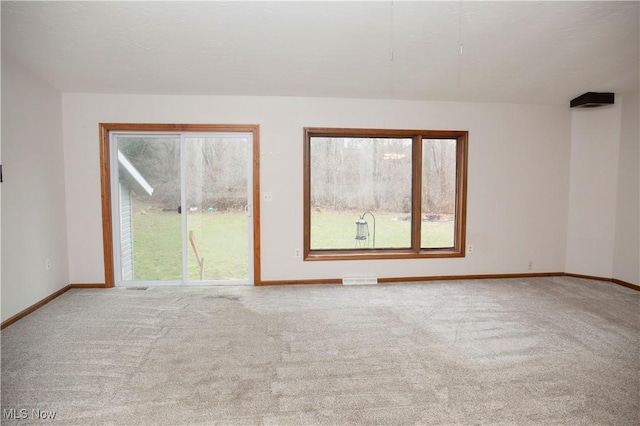 carpeted empty room featuring a wealth of natural light, baseboards, and visible vents