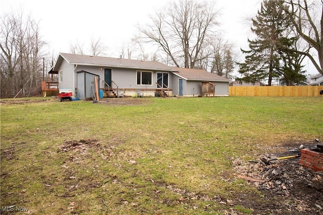 rear view of house featuring fence, a yard, and entry steps