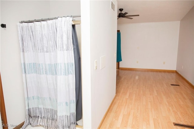 hallway featuring baseboards, wood finished floors, and visible vents
