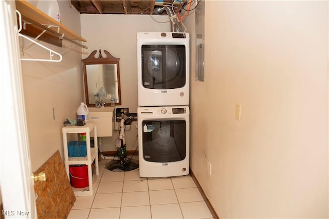 washroom with light tile patterned flooring, stacked washing maching and dryer, a sink, and laundry area