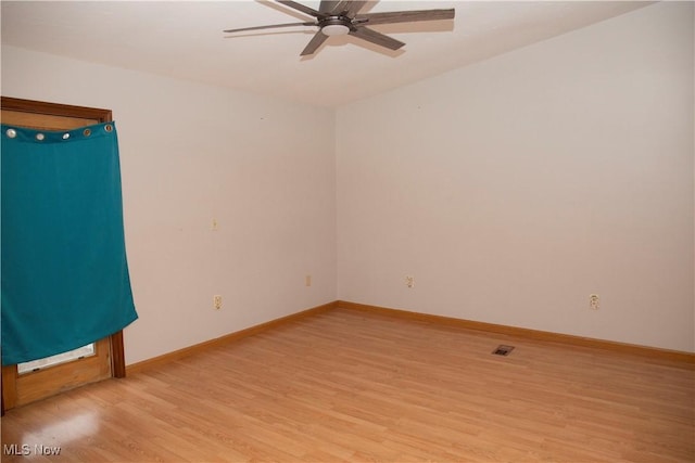 spare room featuring light wood-type flooring, visible vents, a ceiling fan, and baseboards