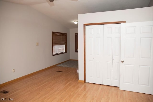 unfurnished bedroom with vaulted ceiling, baseboards, visible vents, light wood-style floors, and a closet